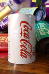 Coke Zero Cans (installation shot), individually measure 12.5″ x 7.5″ x 7.5″, mixed media: screenprints on metalized laminate, cardboard, and polyacrylic, 2011 – 2013. Tastier, Space 1026, Philadelphia, PA.